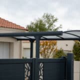 Auvent en aluminium et polycarbonate au dessus d'un carport à l'entrée d'une maison